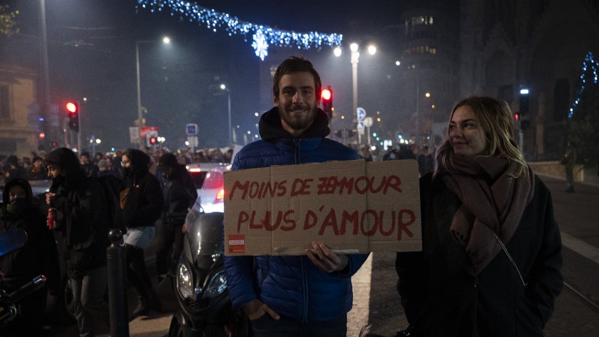 Un manifestant tient une pancarte indiquant "Moins de Zemmour, plus d'amour" à une manifestation sur l'avenue de la Canebière, contre une visite du spécialiste des médias d'extrême-droite Eric Zemmour à Marseille, dans le sud-est de la France, le 26 novembre 2021.
