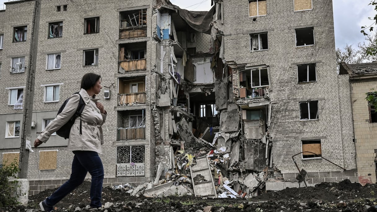 Une femme passe devant un immeuble détruit à Bakhmut dans la région ukrainienne orientale du Donbass le 22 mai 2022.
