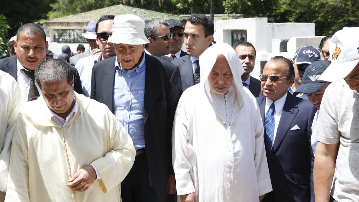 Les visages sont graves, et chacun se prépare à faire une prière en hommage au défunt.
