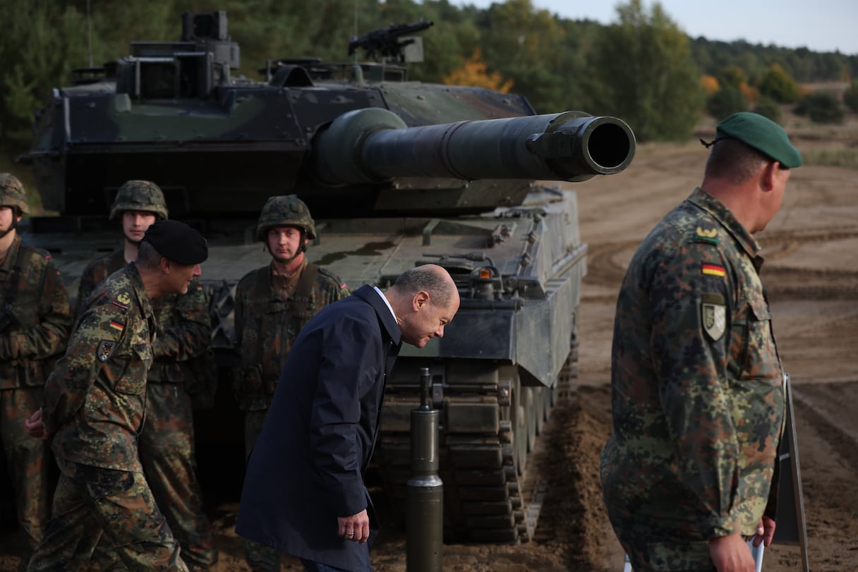 Photo d'archive prise le 17 octobre 2022 montrant le chancelier allemand Olaf Scholz (C) baissant la tête alors qu'il passe devant un char de combat Leopard 2 de la Bundeswehr.