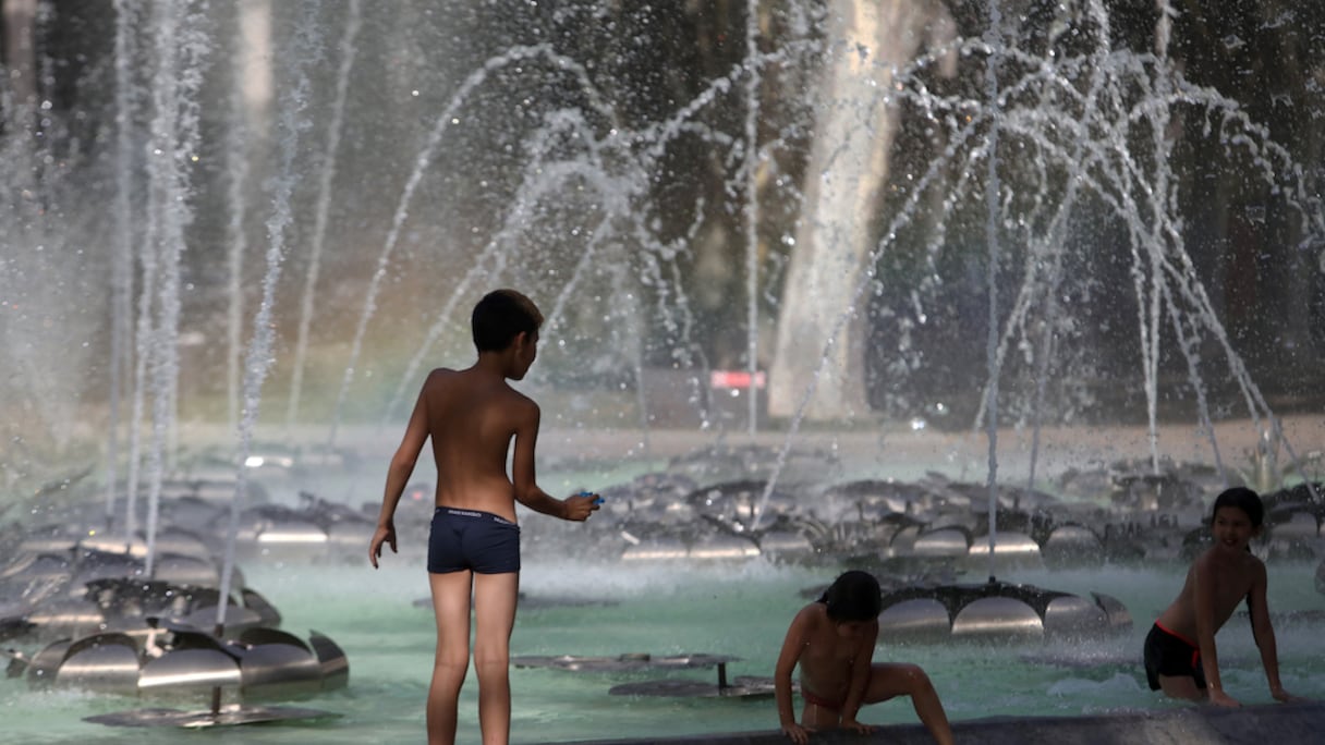 Des enfants jouent dans une fontaine publique pour se rafraîchir dans la ville de Perpignan, dans le sud de la France, le 17 juin 2022.
