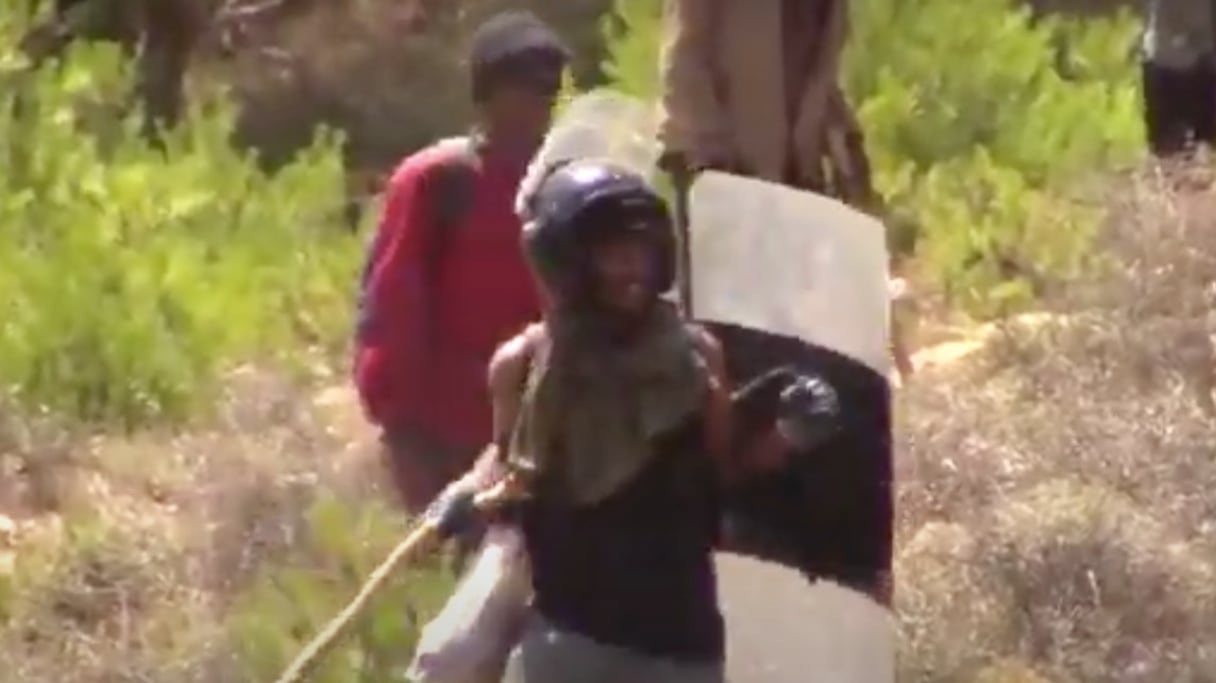 Un migrant, armé d'un bâton, d'un bouclier et d'un casque, se prépare à l'assaut de la clôture de Melilia, le vendredi 24 juin 2022. 
