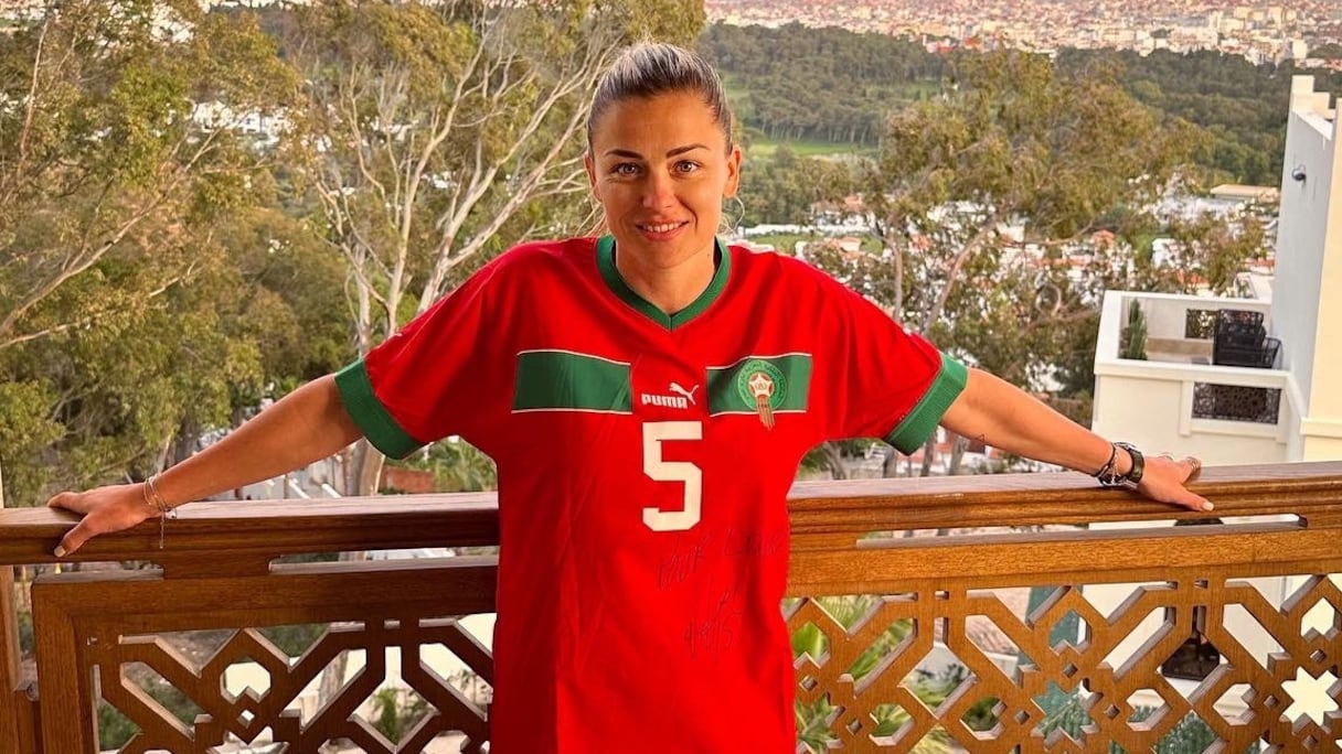 Laure Boulleau, ancienne joueuse du PSG et consultante à Canal+, pose sur un balcon, au Maroc, habillée d'un tee-shirt de l'équipe nationale marocaine.