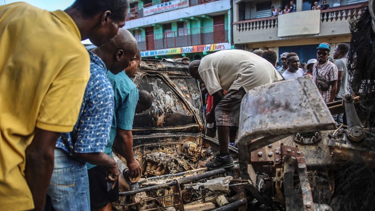 Des hommes ramassent des morceaux d'aluminium sur le site où un camion-citerne a explosé à Cap-Haïtien, en Haïti, le 14 décembre 2021. Au moins 62 personnes ont été tuées lorsque ce camion-citerne à gaz a explosé le 14 décembre 2021 au matin.