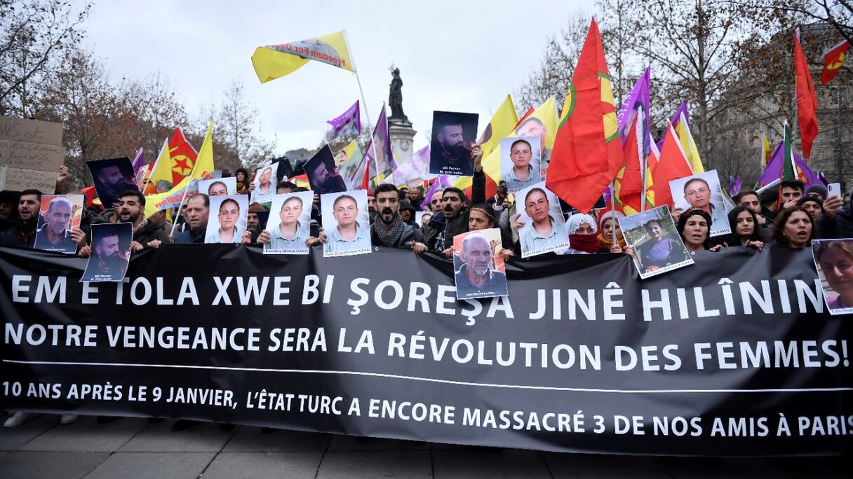 Des manifestants tiennent des drapeaux du Parti des travailleurs kurdes (PKK) et des portraits de victimes lors d'une manifestation, un jour après qu'un homme armé a ouvert le feu sur un centre culturel kurde tuant trois personnes, sur la place de la République à Paris le 24 décembre 2022.
