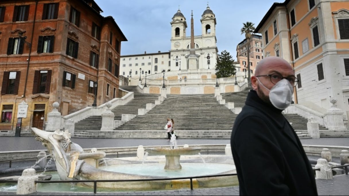 Un homme portant un masque de protection passe devant les marches désertes menant à la place d'Espagne, dans le centre de Rome, le 12 mars 2020.
