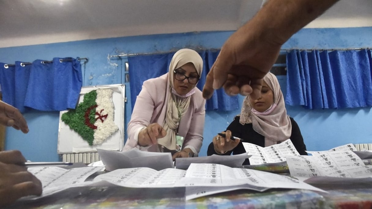 Le personnel électoral algérien compte les bulletins de vote pour les élections législatives dans un bureau de vote à Bouchaoui, à la périphérie ouest de la capitale, Alger, le 12 juin 2021.
