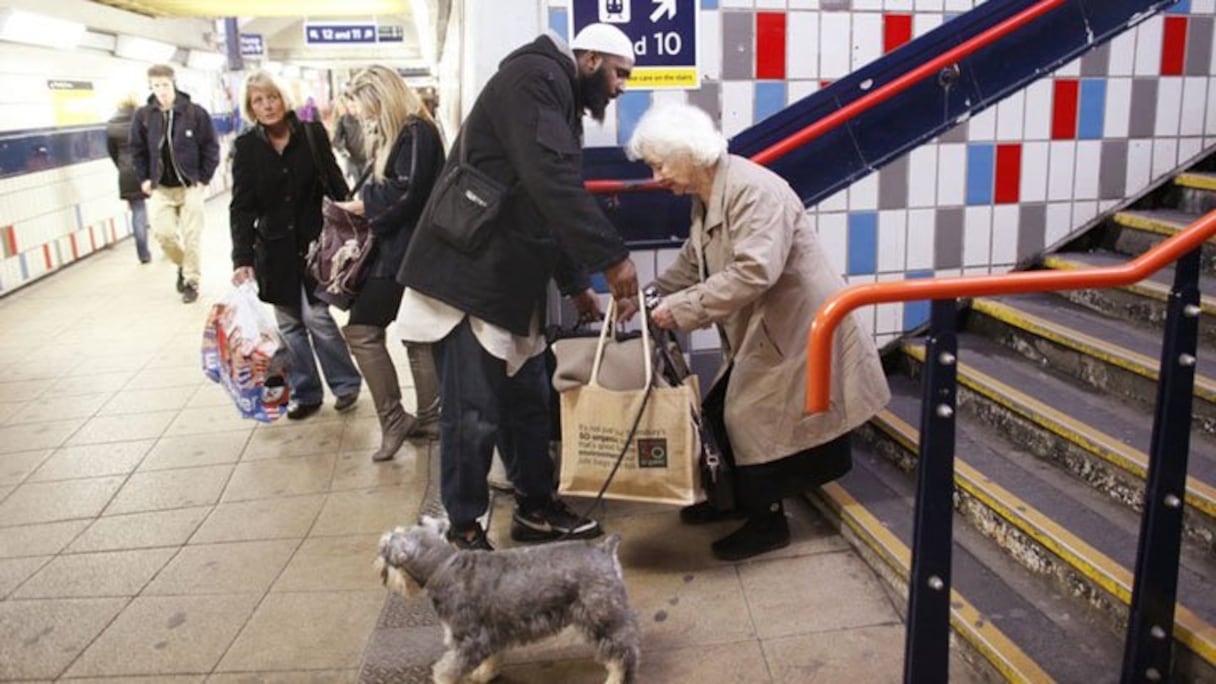 Un homme s'arrête pour aider une dame âgée à porter ses courses. 

