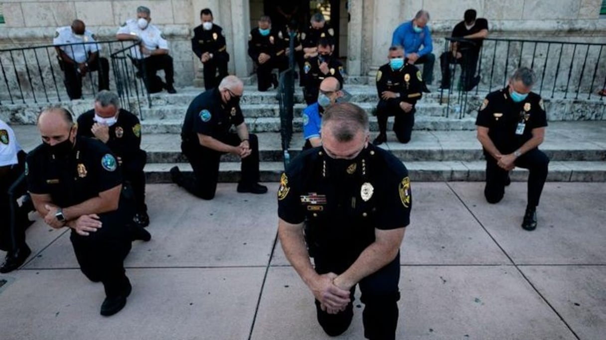 Des policiers américains, genou à terre, en signe de soutien aux manifestants.
