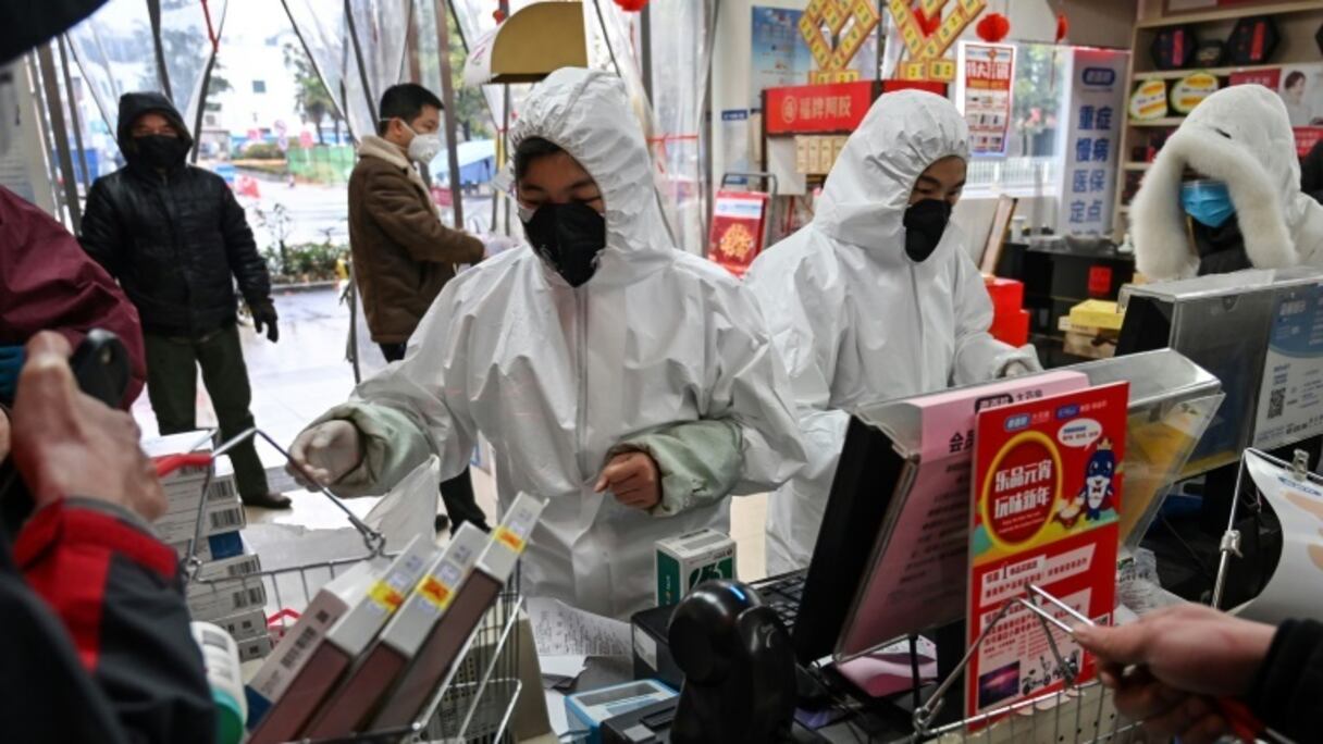 Des employés en pharmacie, en combinaison et masque de protection, servent des clients, le 25 janvier 2020 à Wuhan, épicentre du nouveau coronavirus.
