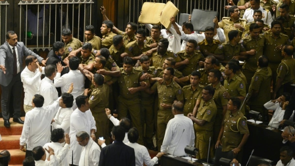 La police a dû escorter le président du parlement du Sri Lanka Karu Jayasuriya à l'intérieur de l'assemblée face aux députés opposés qui lui jetaient des objets à la figure, le 16 novembre 2018.
