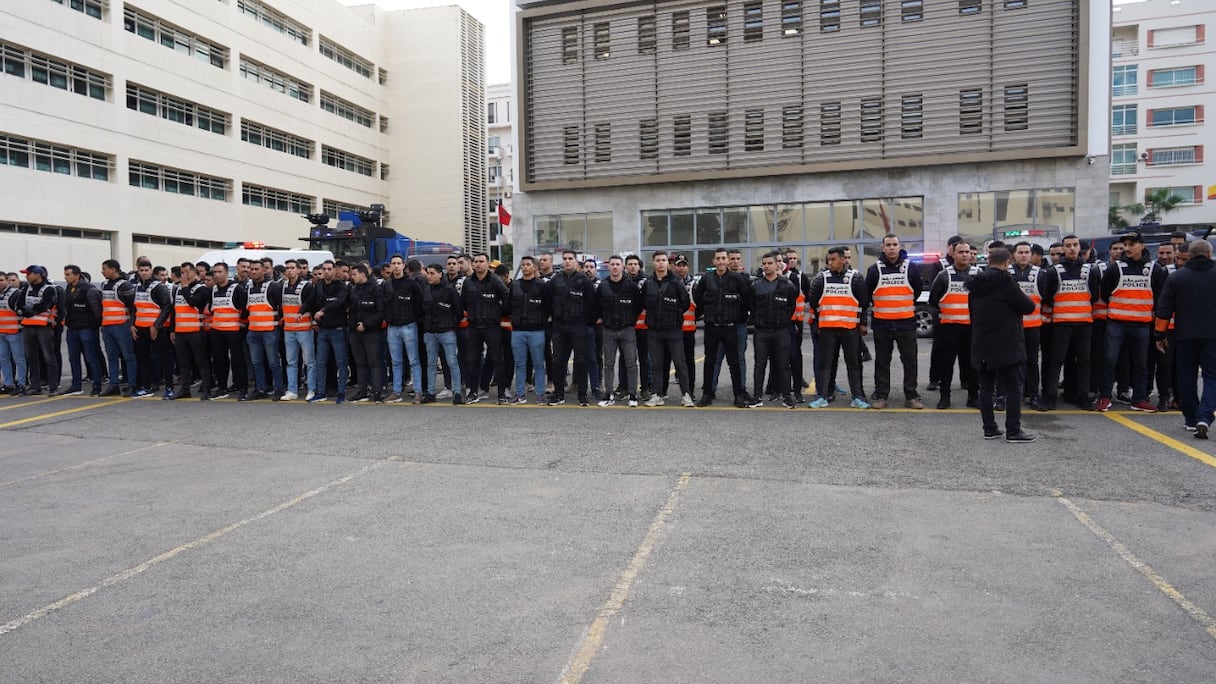 Passage en revue d'agents de police en uniforme et en civil, dans l'enceinte d'une préfecture.
