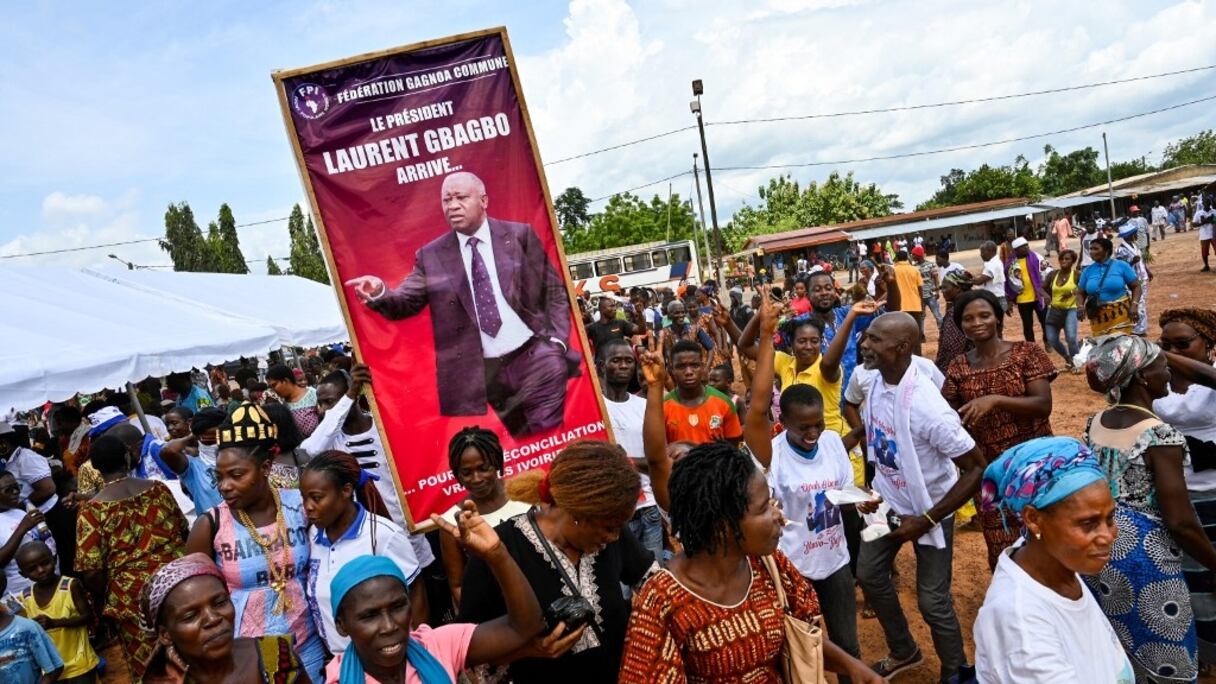 Des supporters tiennent une affiche: "le président Laurent Gbagbo arrive pour une vraie réconciliation des Ivoiriens", après un rassemblement en prélude à la réception de Gbagbo dans sa ville natale de Mama, à Gagnoa, le 13 juin 2021.
