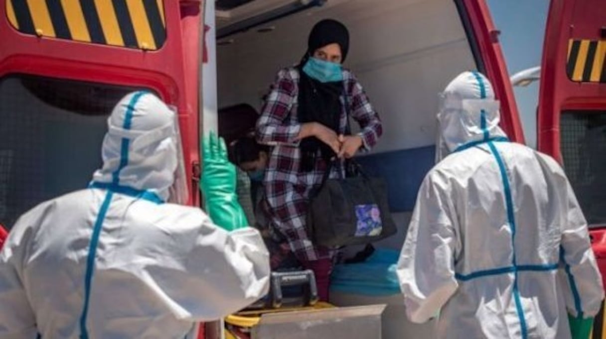 Une patiente atteinte par le Covid-19 est accueillie par des soignants à son arrivée dans l'hôpital de campagne de Benguerir.
