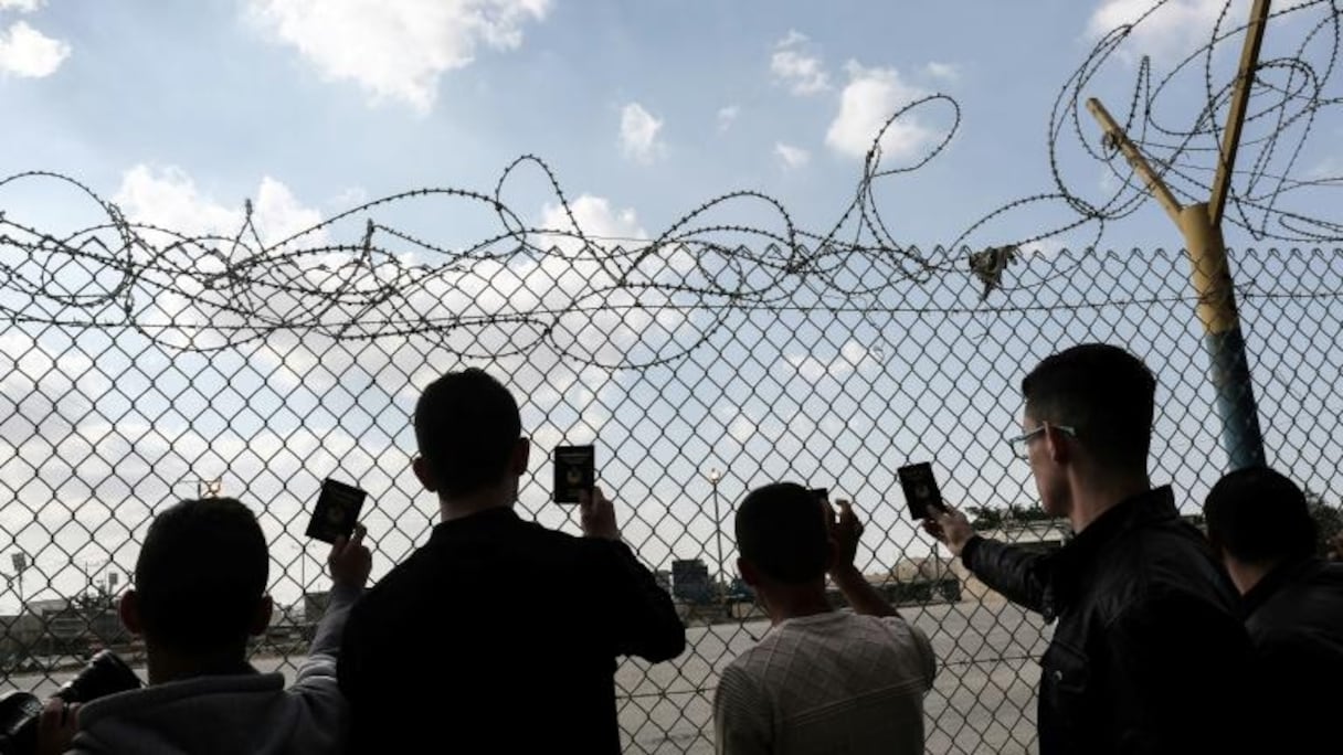 De jeunes Palestiniens montrent leur passeport alors qu'ils attendent de pouvoir traverser le point de passage de Rafah, avec l'Égypte.
