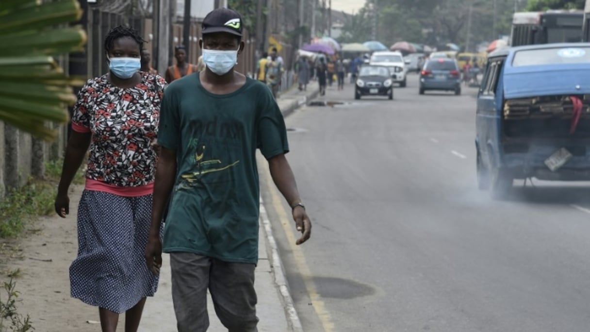 Des passants protégés par des masques dans un quartier de Lagos, le 28 février 2020.
