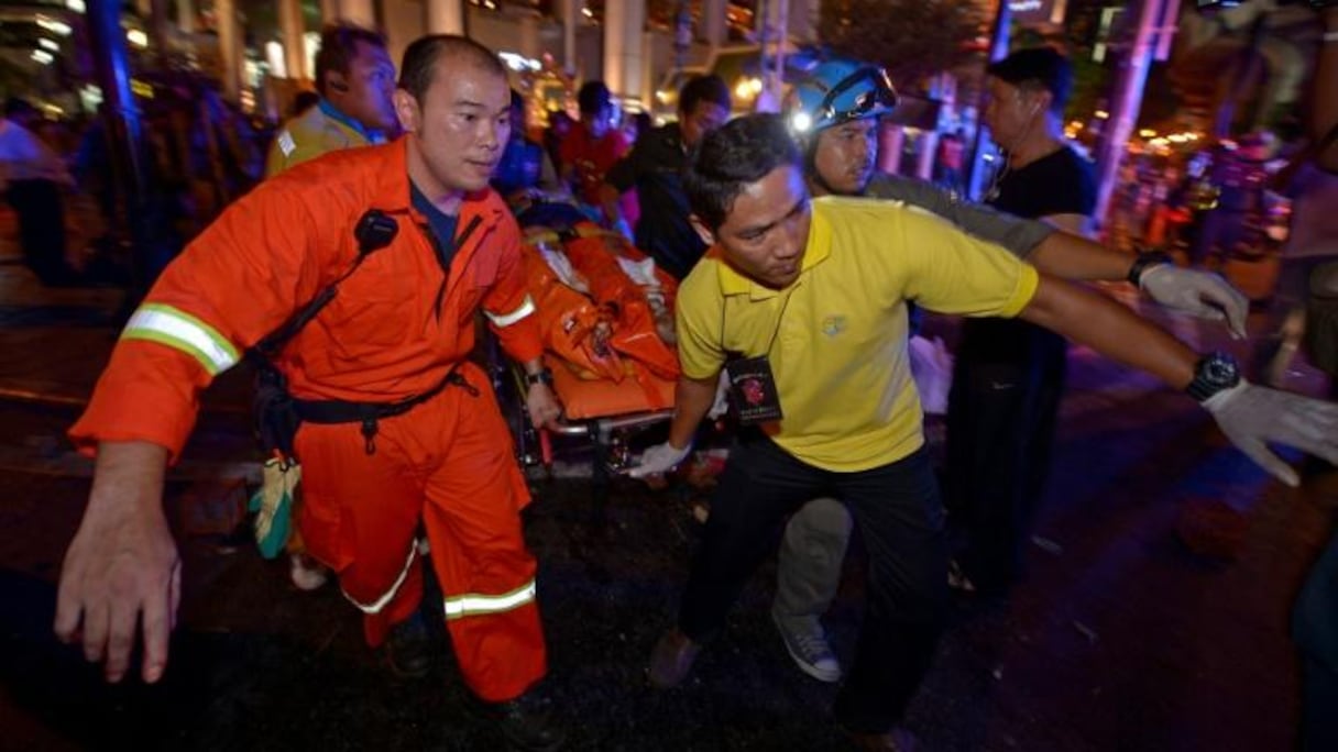 Des sauveteurs portent un blessé après l'explosion d'une bombe à l'extérieur du sanctuaire d'Erawan, situé en plein coeur de la capitale thaïlandaise, le 17 août 2015.
