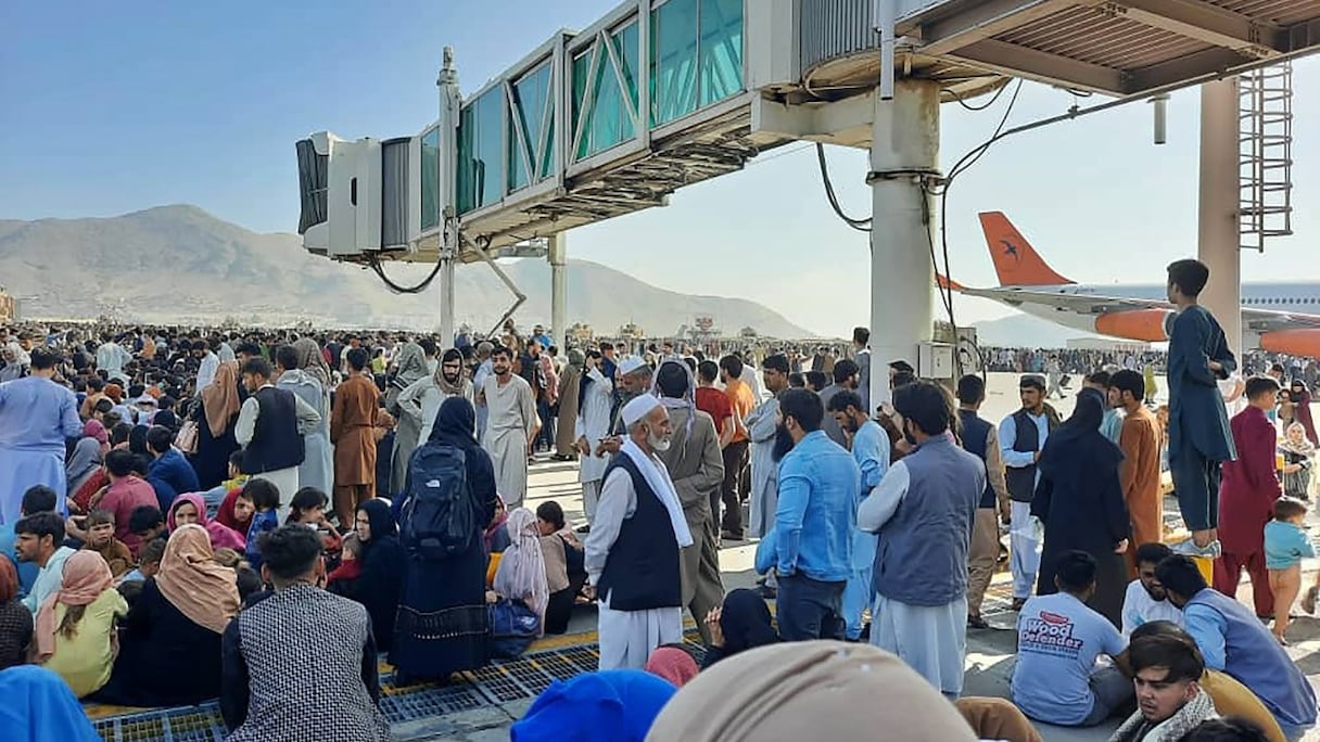 Des Afghans se pressent sur le tarmac de l'aéroport de Kaboul le 16 août 2021 pour fuir le pays alors que les talibans contrôlent l'Afghanistan après que le président Ashraf Ghani a fui le pays et reconnu que les insurgés avaient gagné une guerre de 20 ans.
