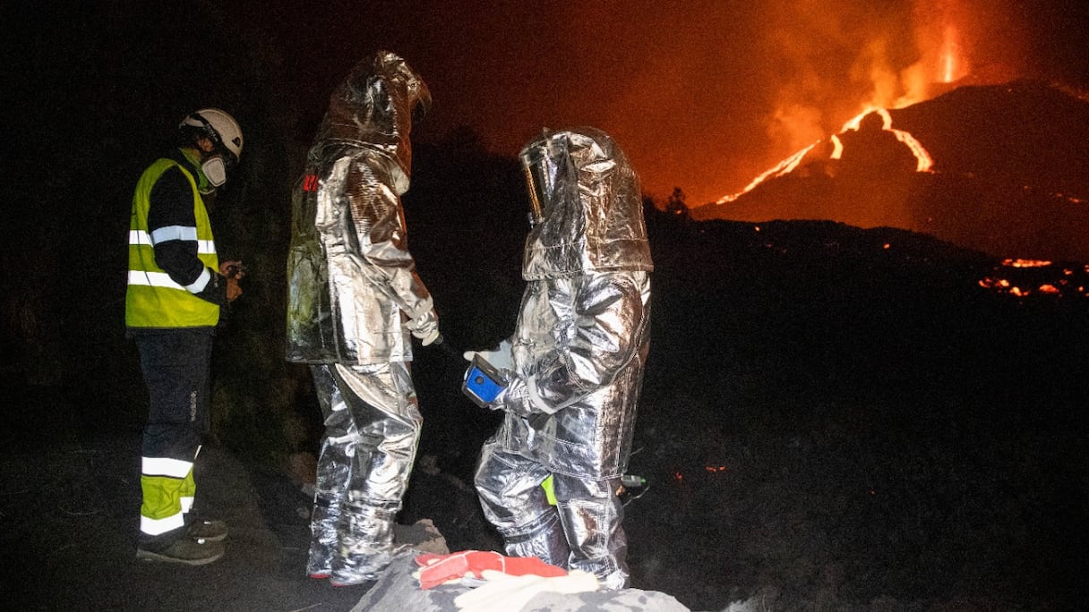 Des membres du Groupe d'intervention d'urgence technologique et environnementale et un membre de l'Institut géologique et minier espagnol suivent l'évolution d'une coulée de lave, près du Cumbre Vieja en éruption, sur l'île de La Palma, aux Canaries, le 16 octobre 2021.
