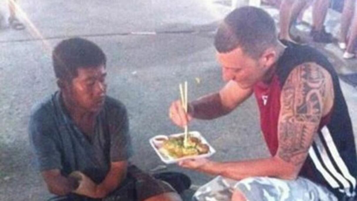 Il offre son repas à un sans-abri et le nourrit car le jeune homme est amputé des deux bras. 
