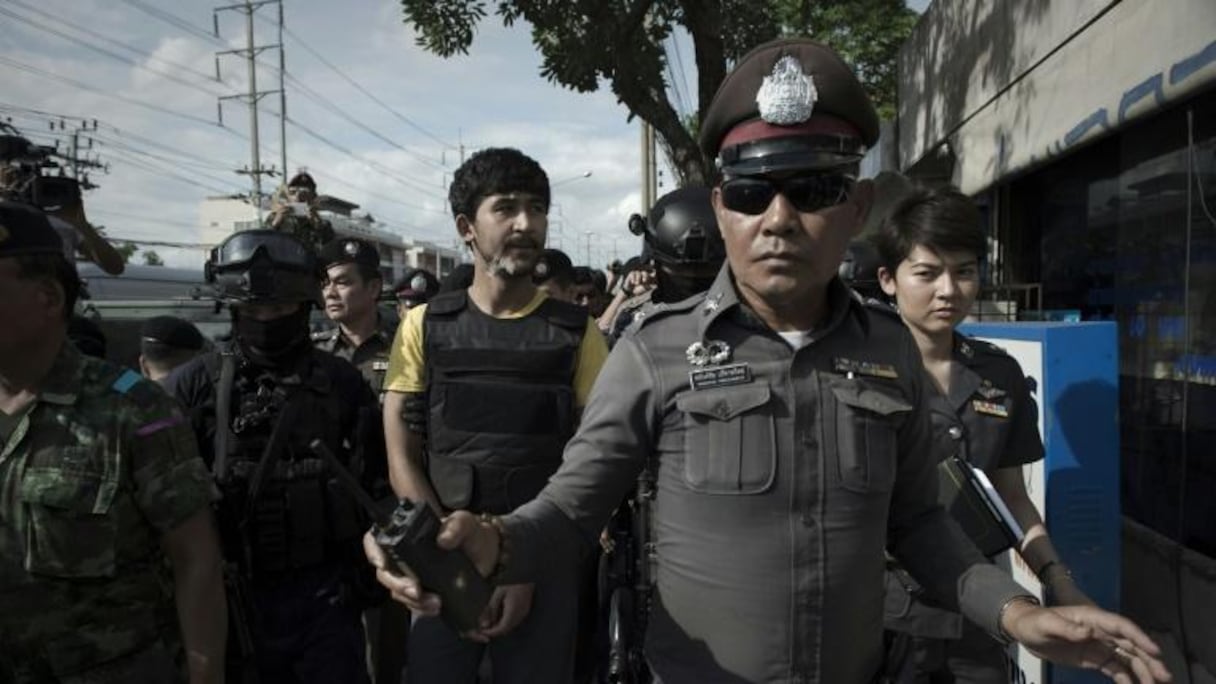 Un suspect dans l'enquête sur l'attentat de Bangkok, Yusufu Mieraili (c), escorté par des policiers lors de la reconstitution des faits, le 8 septembre 2015 à Bangkok.
