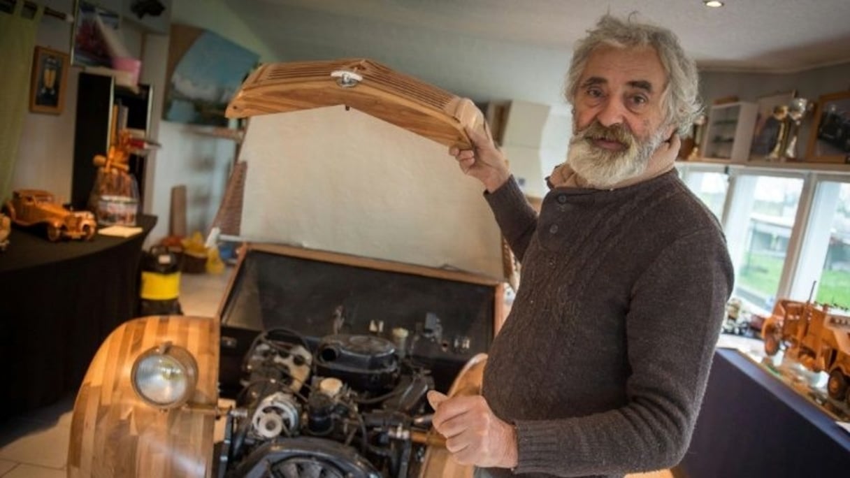 Michel Robillard montre le moteur de la 2 CV Citroen en bois qu'il vient de fabriquer. 
