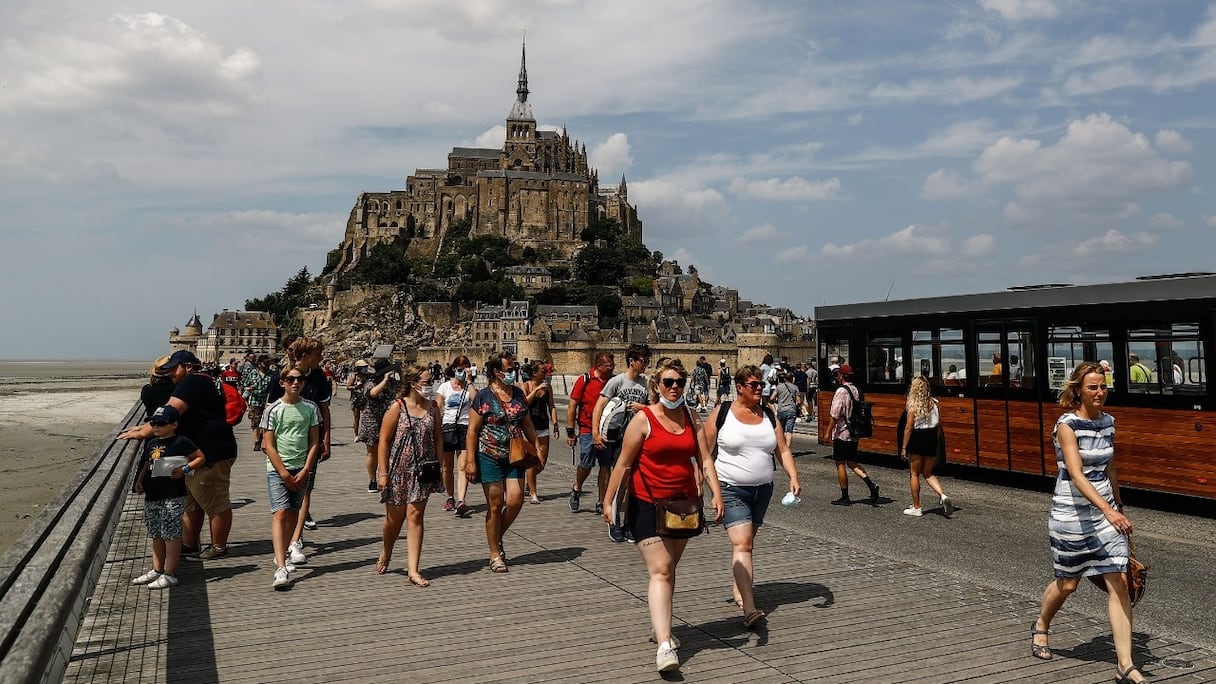 Des touristes marchent devant le Mont-Saint-Michel, en Normandie, dans le nord-ouest de la France, le 22 juillet 2021.
