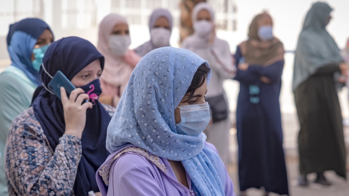 Des personnes attendent leur tour devant un centre de vaccination Covid-19, dans le contexte de l'opération «vaccinodrome intelligent», au quartier Errahma, près de Casablanca, le 9 août 2021. 
