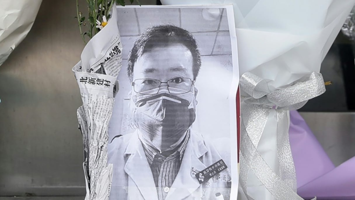 Une photo du médecin Li Wenliang, devant laquelle a été déposé un bouquet de fleurs, devant une aile de l'hôpital de Wuhan, en Chine, le 7 février.
