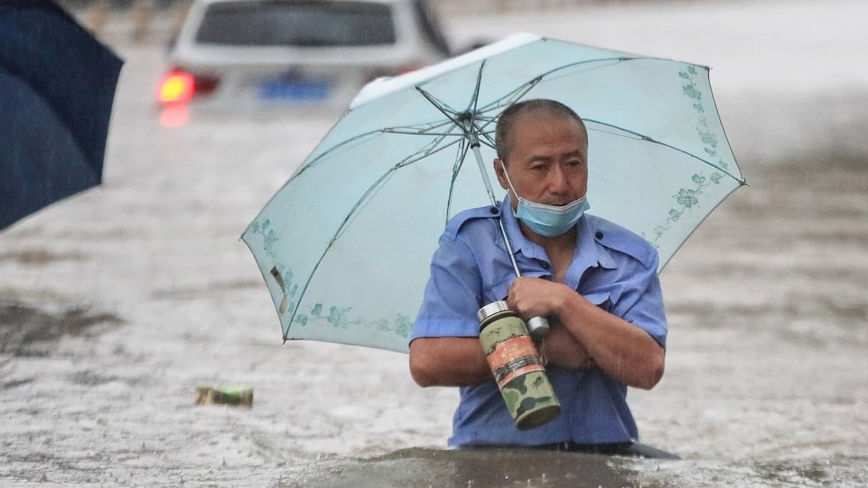 Un homme patauge dans les eaux d'une crue, le long d'une rue, à la suite de fortes pluies à Zhengzhou, à 700 km de Pékin, dans la province centrale du Henan, en Chine, le 20 juillet 2021. 
