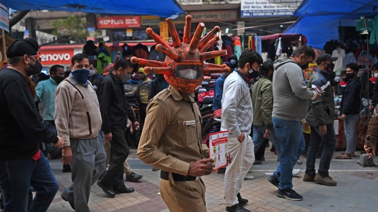 Le militant d'une ONG sensibilise les passants aux risques sanitaires inhérents au coronavirus, à New Delhi, le 25 novembre 2020. 
