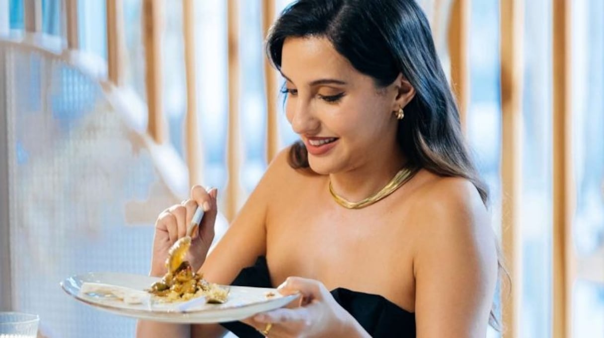 Nora Fatehi, invitée de l'émission Stars vs Food, déguste le poulet aux citrons confits et olives qu'elle vient de préparer. 
