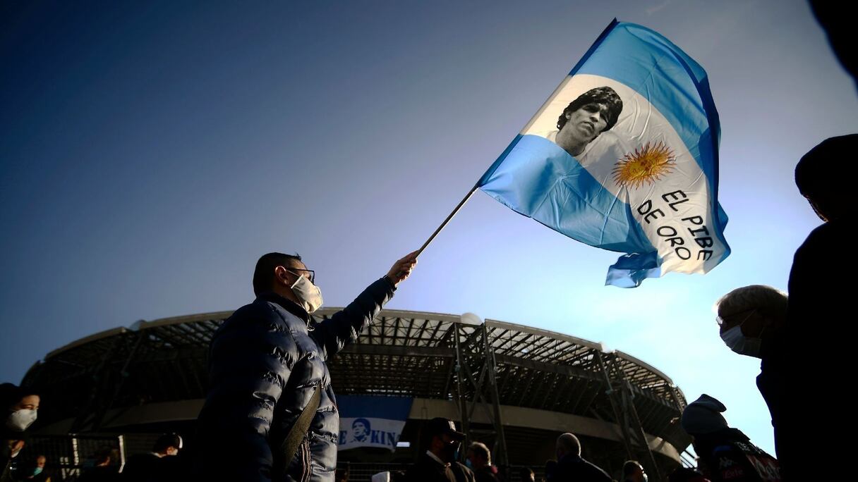 Un homme avec un drapeau orné d'une photo de Diego Maradona devant le stade de Naples le 26 novembre 2020.
