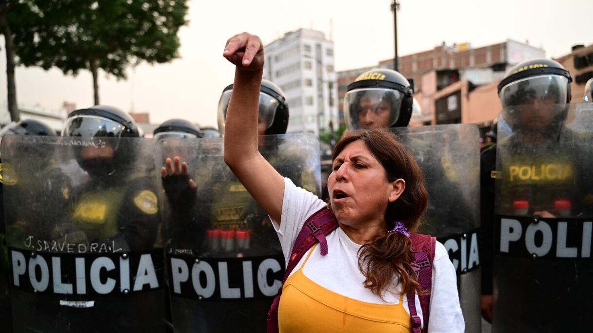 Une manifestante pro-Pedro Castillo se tient devant la police anti-émeute, exigeant la libération de l'ex-président, à Lima, le 14 décembre 2022. Le Pérou a la veille proclamé l'état d'urgence, après un bilan de 7 morts, dus à de violentes manifestations.
