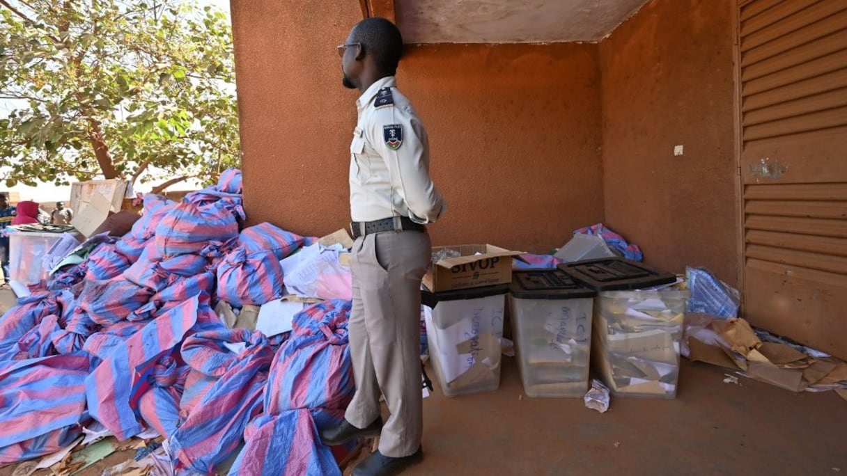 Un officier de police surveille des urnes remplies de bulletins de vote, dans un bureau de la Commission électorale nationale indépendante (CENI) à Ouagadougou, le 24 novembre 2020.
