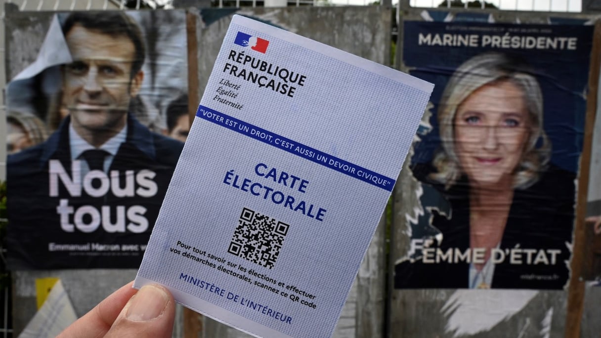 Carte électorale et affiches de Marine Le Pen, candidate du Parti d'extrême-droite Rassemblement national (à droite), et du président sortant et candidat à sa réélection Emmanuel Macron, au nom de La République en marche, à Montpellier, le 21 avril 2022.
