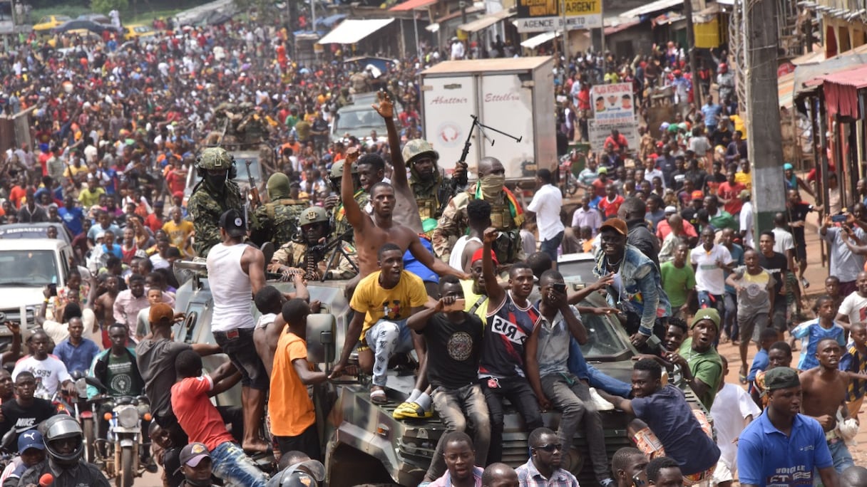 La foule célèbre l'arrestation du président guinéen Alpha Condé dans les rues de Conakry, avec des membres des forces armées guinéennes, lors d'un coup d'Etat, le 5 septembre 2021.
