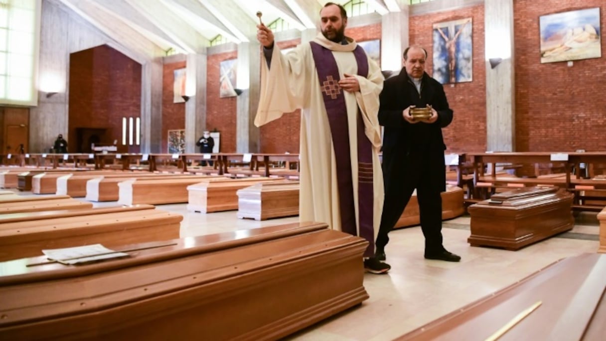 Un prêtre bénit les cercueils des personnes décédées du coronavirus dans l'église San Giuseppe, le 28 mars 2020 à Seriate, en Italie.
