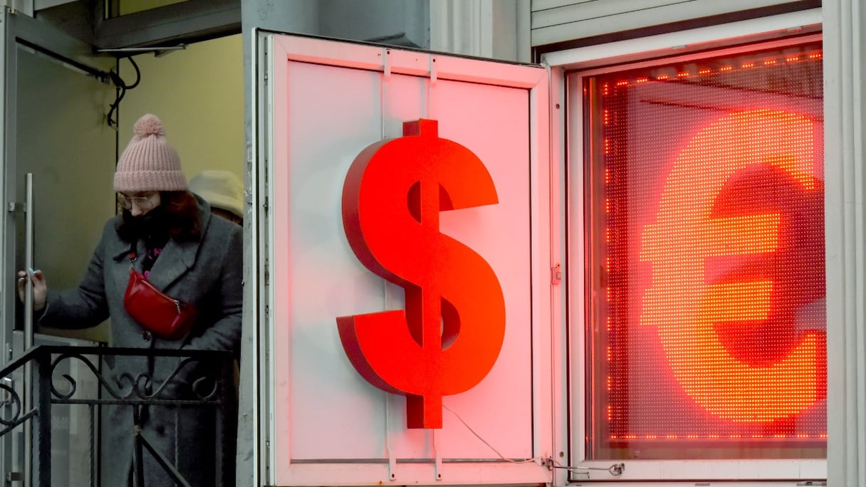 Une femme quitte un bureau de change où le symbole du dollar américain et celui de l'euro sont affichés à Saint-Pétersbourg, en Russie, le 2 mars 2022.
