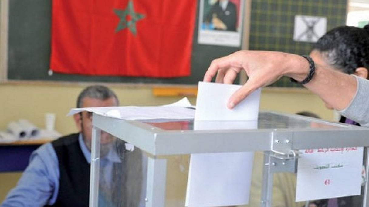 Une urne transparente reçoit un bulletin de vote.
