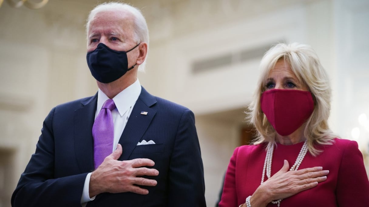 Le président américain Joe Biden et la première Dame Jill Biden ont la main sur le cœur alors que retentit l'hymne national des Etats-Unis, lors d'un office virtuel retransmis depuis la Cathédrale nationale de Washington, le 21 janvier 2021, à la Maison Blanche. 
