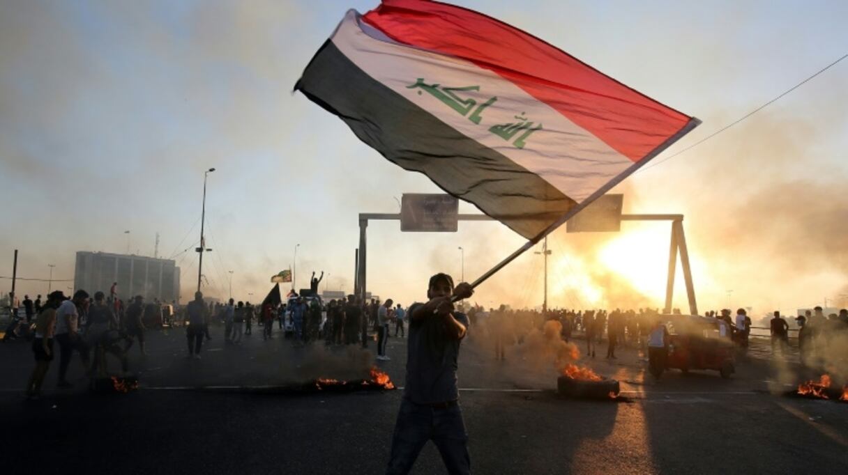 Dans un contexte de tensions sociales, un Irakien agite le drapeau national le 5 octobre 2019, dans le centre de Bagdad. 
