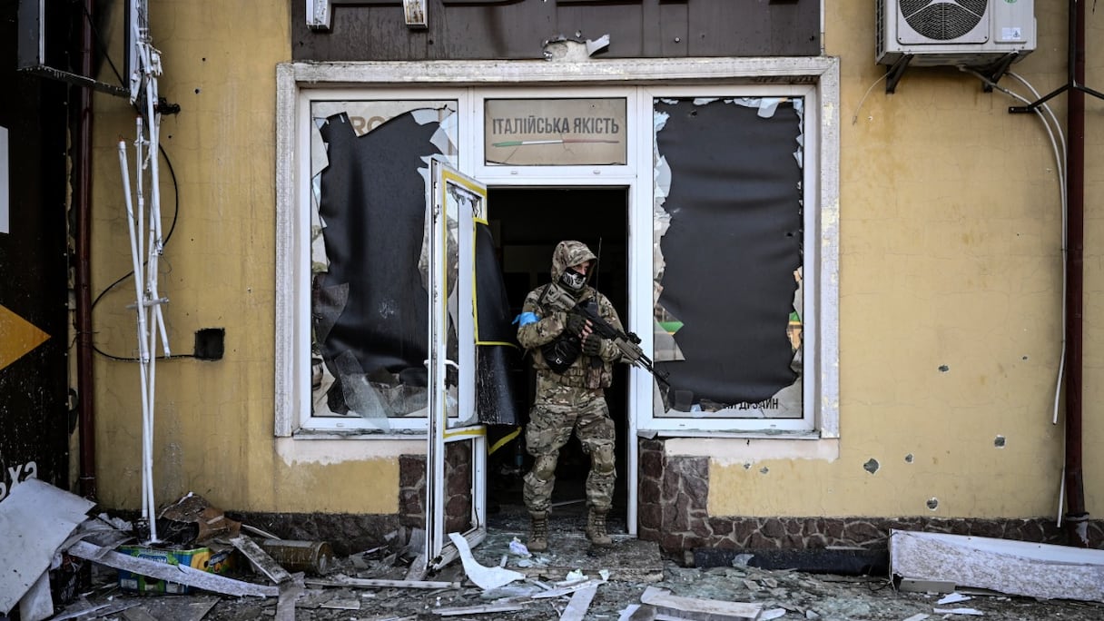 Un militaire ukrainien sort d'un bâtiment endommagé après un bombardement à Kiev, le 12 mars 2022, alors que les forces russes sont positionnées autour de la capitale ukrainienne.
