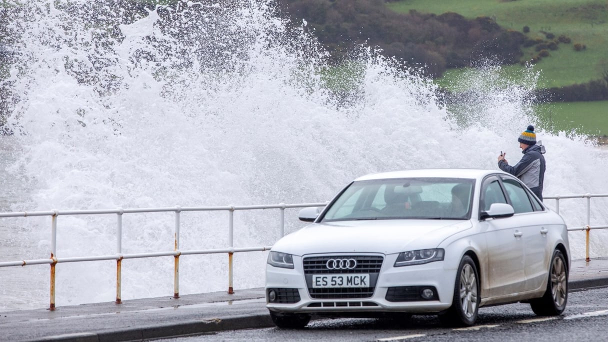 Une personne photographie la mer alors que les vagues s'écrasent sur la digue à Carnlough, en Irlande du Nord, le 18 février 2022, alors que la tempête Eunice draine des vents violents à travers le pays.
