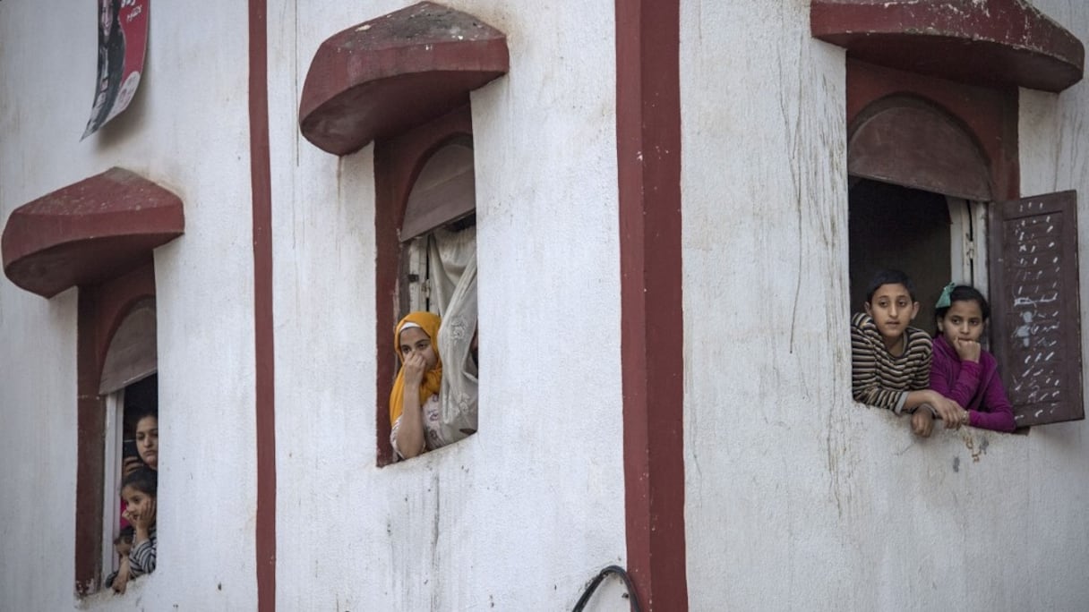 Des Marocains confinés à leur domicile dans le quartier populaire de Takaddoum, à Rabat, observent une scène au bas de leur rue, en cette période d'état d'urgence sanitaire sur le territoire national.
