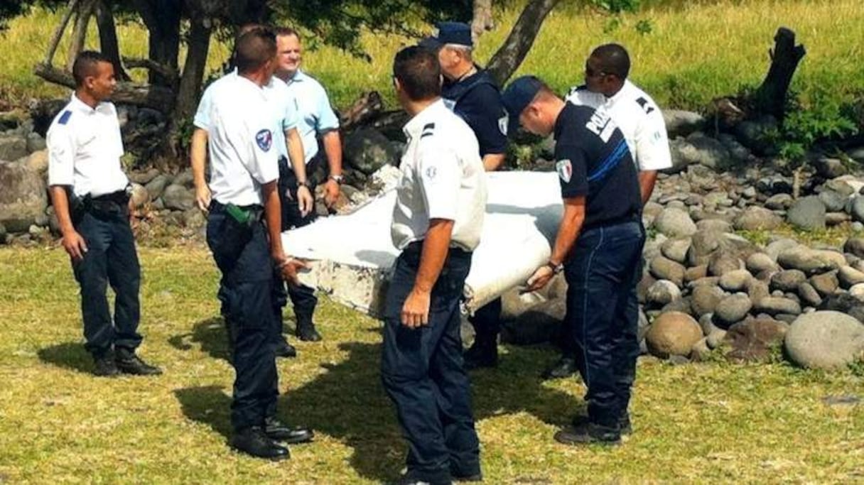 Des policiers transportent des débris d'un avion non identifié retrouvé au large de La Réunion, le 29 juillet 2015.
