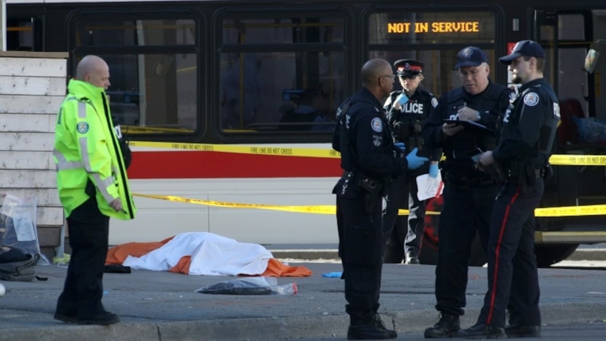 Des policiers près d'un corps caché par un drap, le 23 avril 2018 à Toronto, au Canada, après qu'un homme au volant d'une camionnette a fauché une dizaine de piétons.
