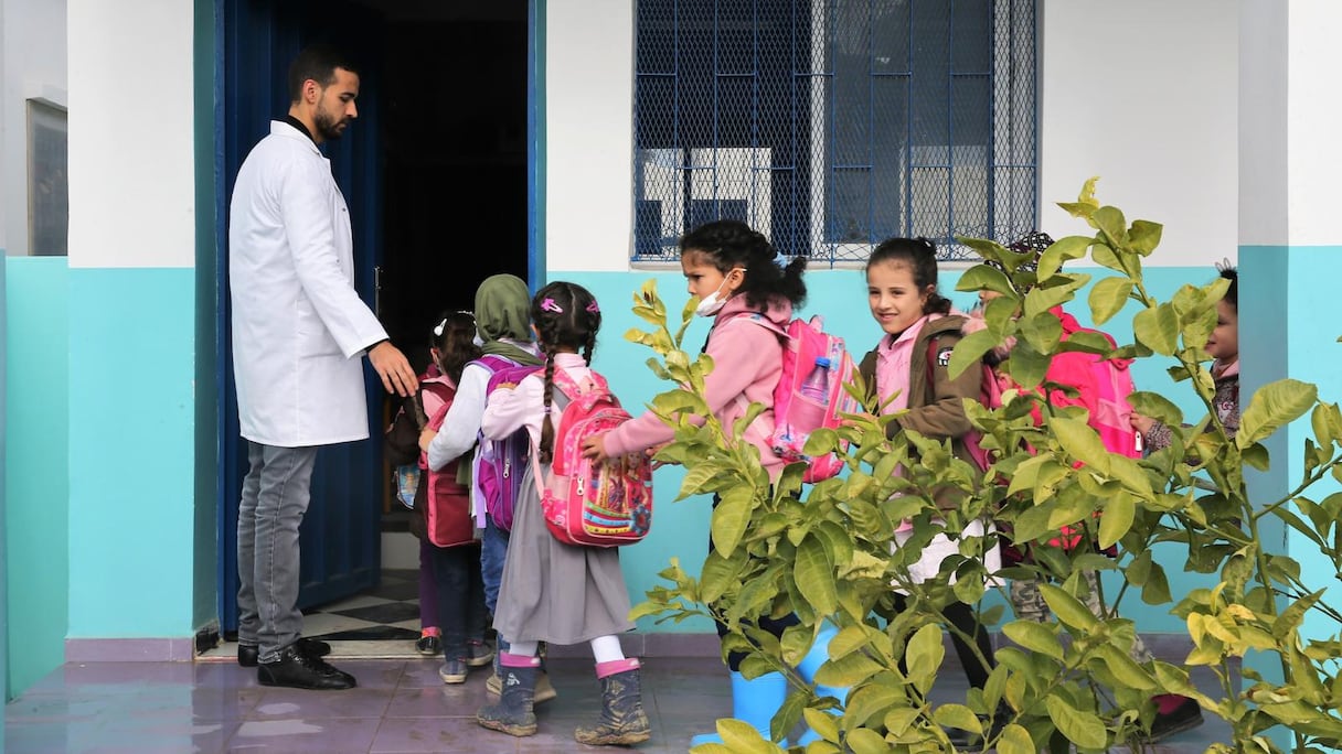 Un enseignant accueille des élèves d'une école primaire dans la commune de Melloussa (province de Fahs-Anjra). 
