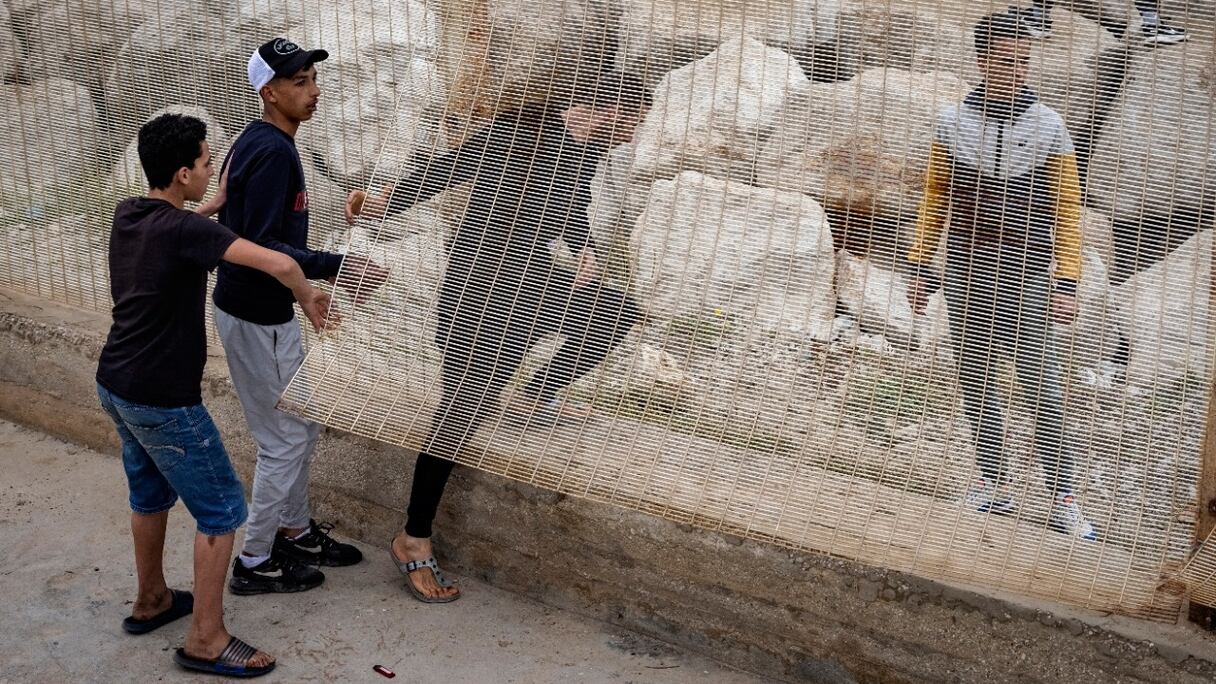 Des migrants marocains glissent à travers une clôture frontalière dans la ville de Fnideq, dans le nord du pays, pour tenter de traverser la frontière entre le Maroc et l'enclave nord-africaine de Sebta, en Espagne, le 18 mai 2021.
	 
