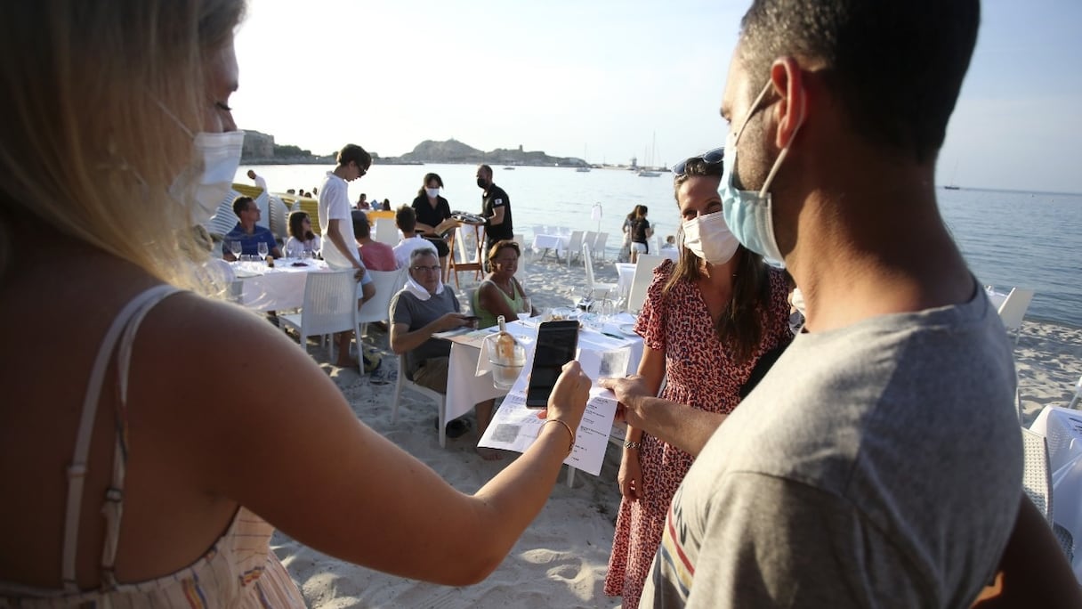 Un restaurateur vérifie les pass sanitaires de ses clients avant de les installer à une table de son restaurant, dans la partie nord de l'île de Corse, le 23 juillet 2021.
